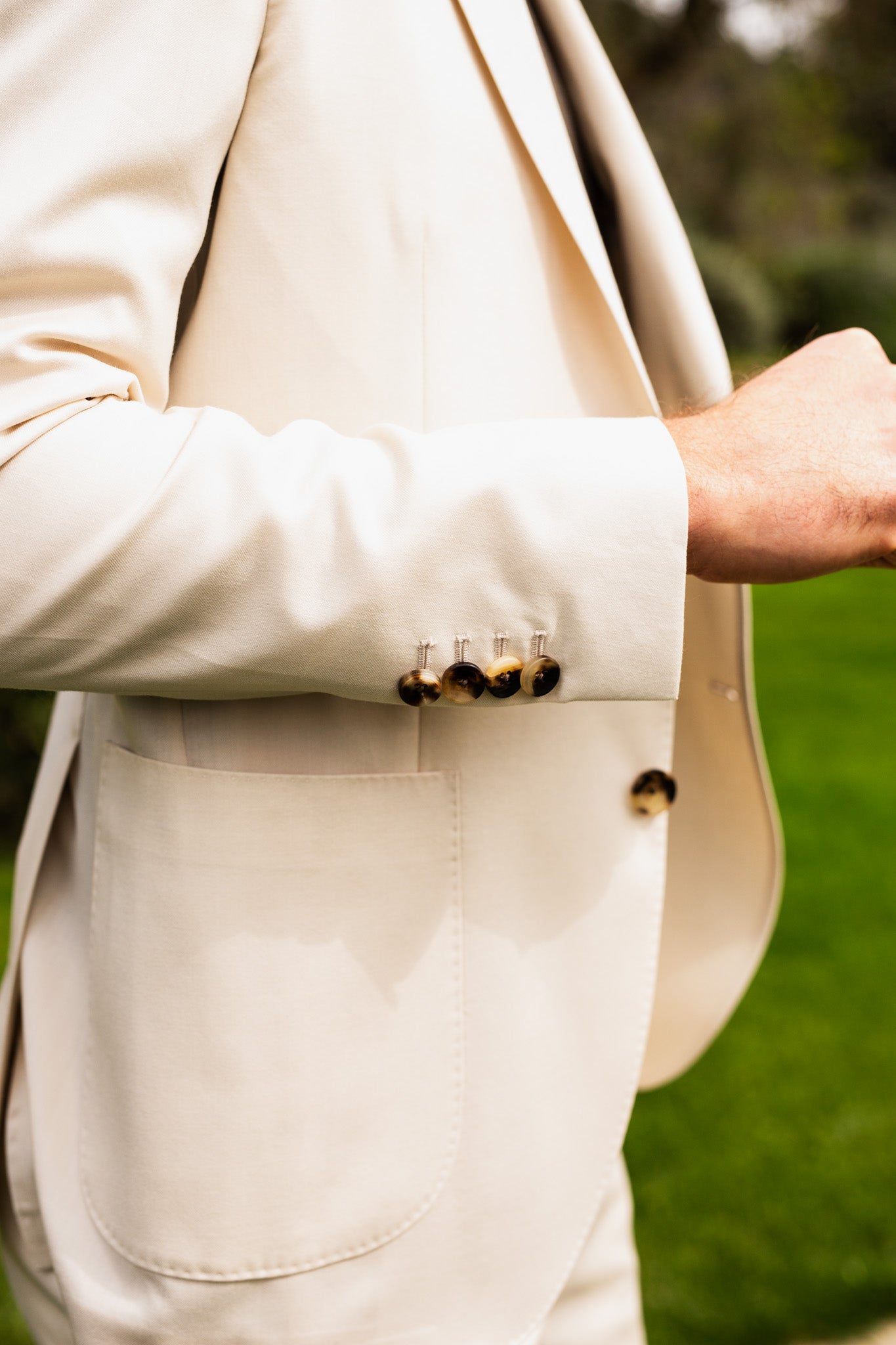 Close up look at details on beige suit jacket, 4 brown tortoise buttons on sleeve cuff