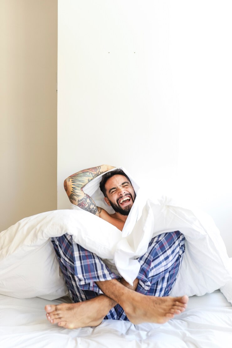 man-sitting-bed-laughing_23-2147912044.jpg